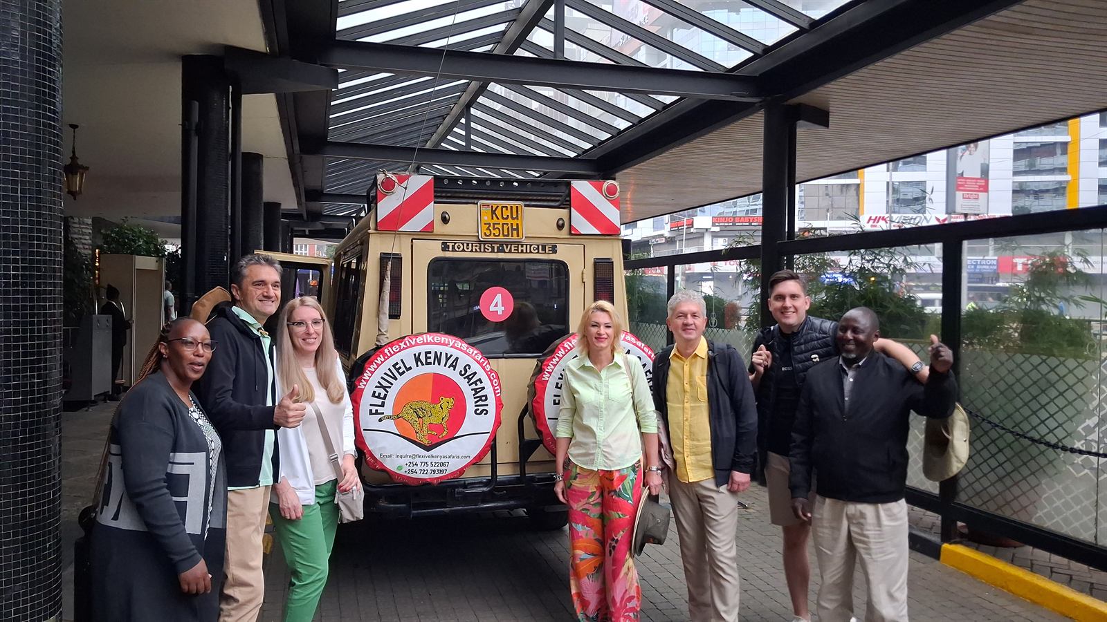 Flexivel Kenya Safaris clients and team beside a branded safari vehicle