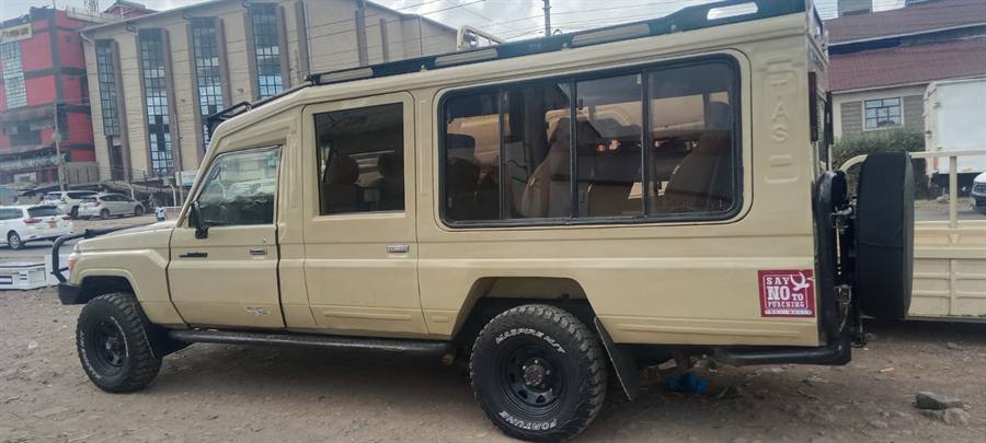 A cream extended Land Cruiser 4x4 safari vehicle with a pop-up roof parked in a town