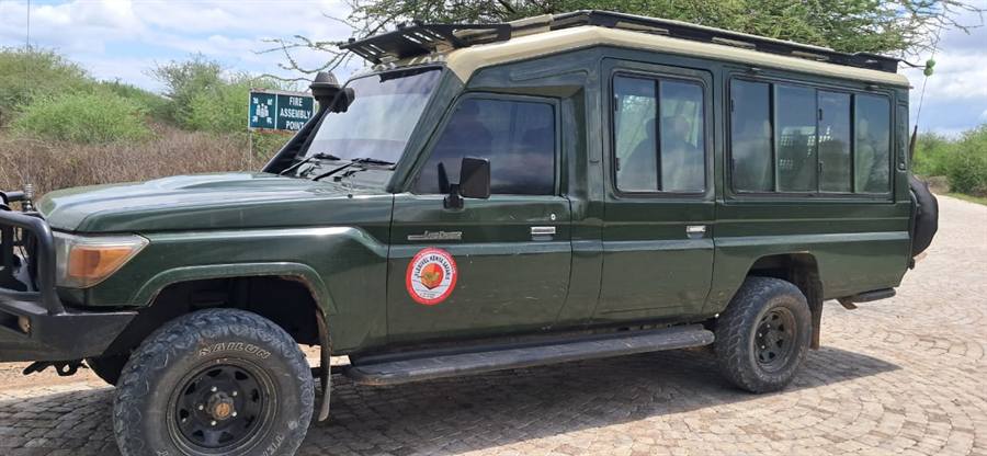 Side view of a dark green extended Land Cruiser 4x4 safari vehicle with a Flexivel Kenya Safaris logo on the door